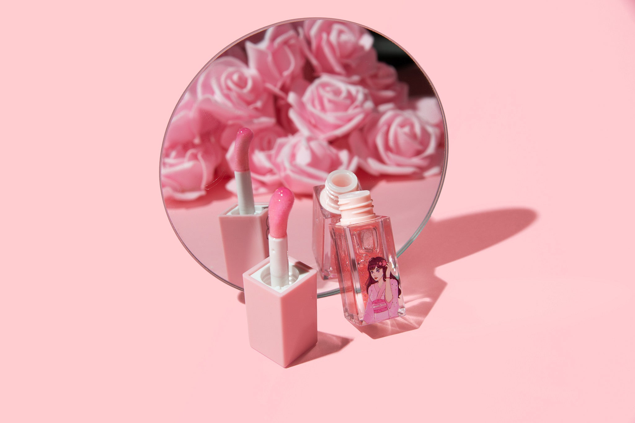 Makeup products with a mirror showing pink roses on a pink background