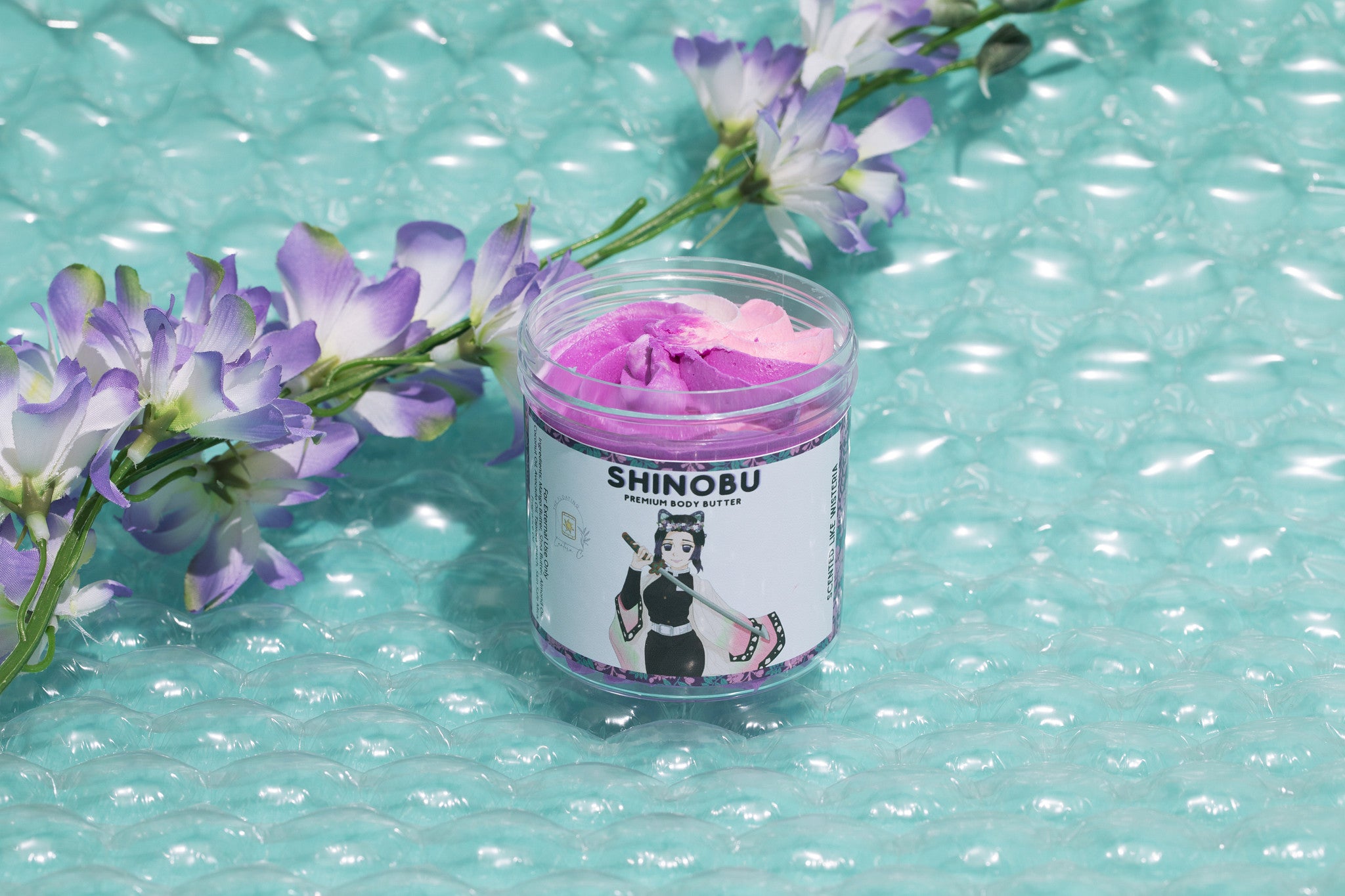 Body Butter with a label on a turquoise surface with purple flowers